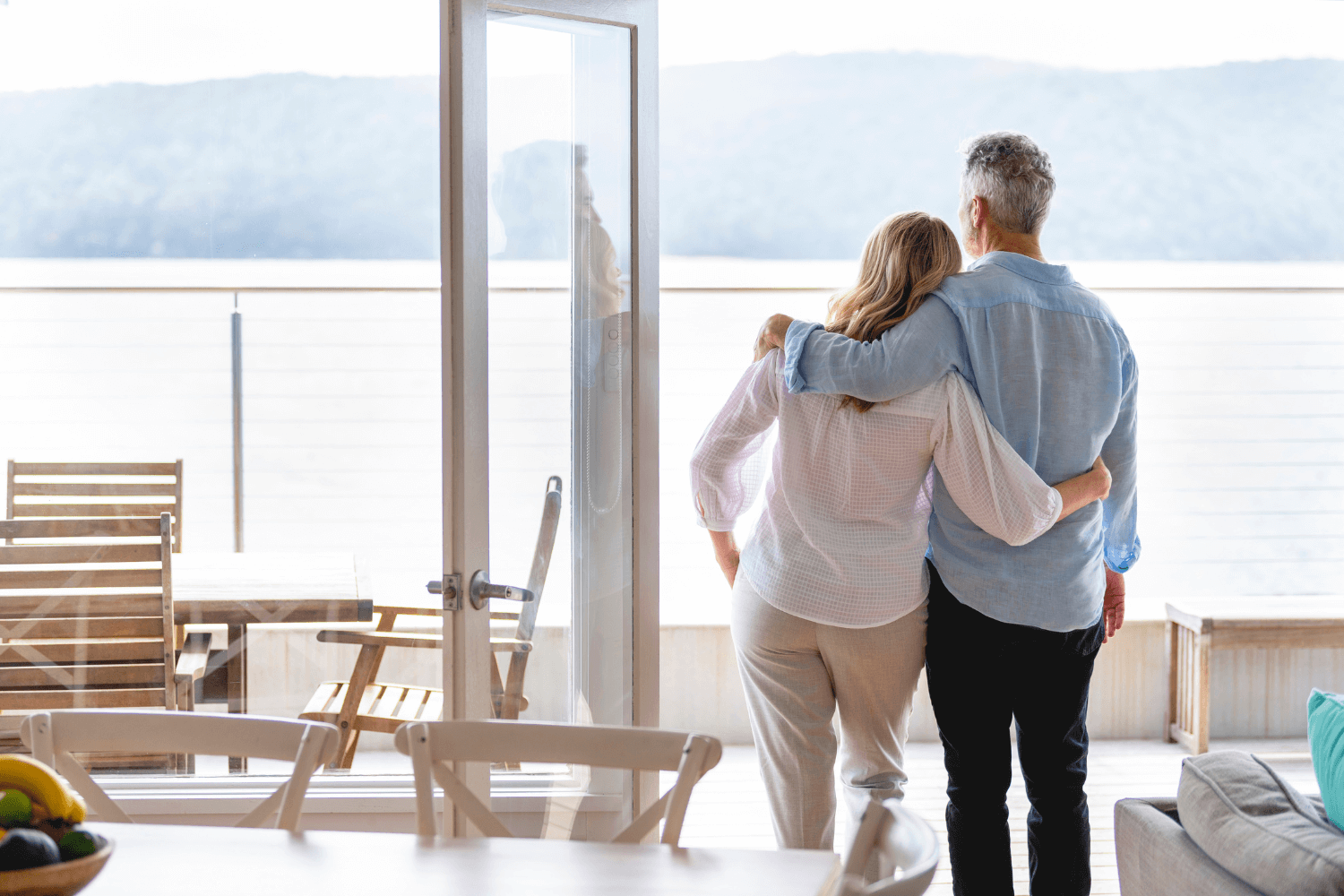 Couple standing in their home looking out at the water