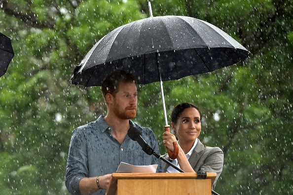 Meghan markle holds umbrella for prince harry in dubbo