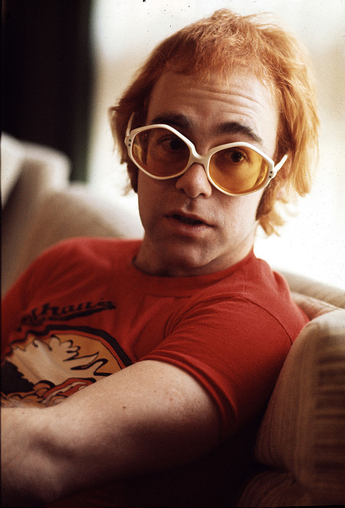 Elton John wearing a pair of white, round glasses