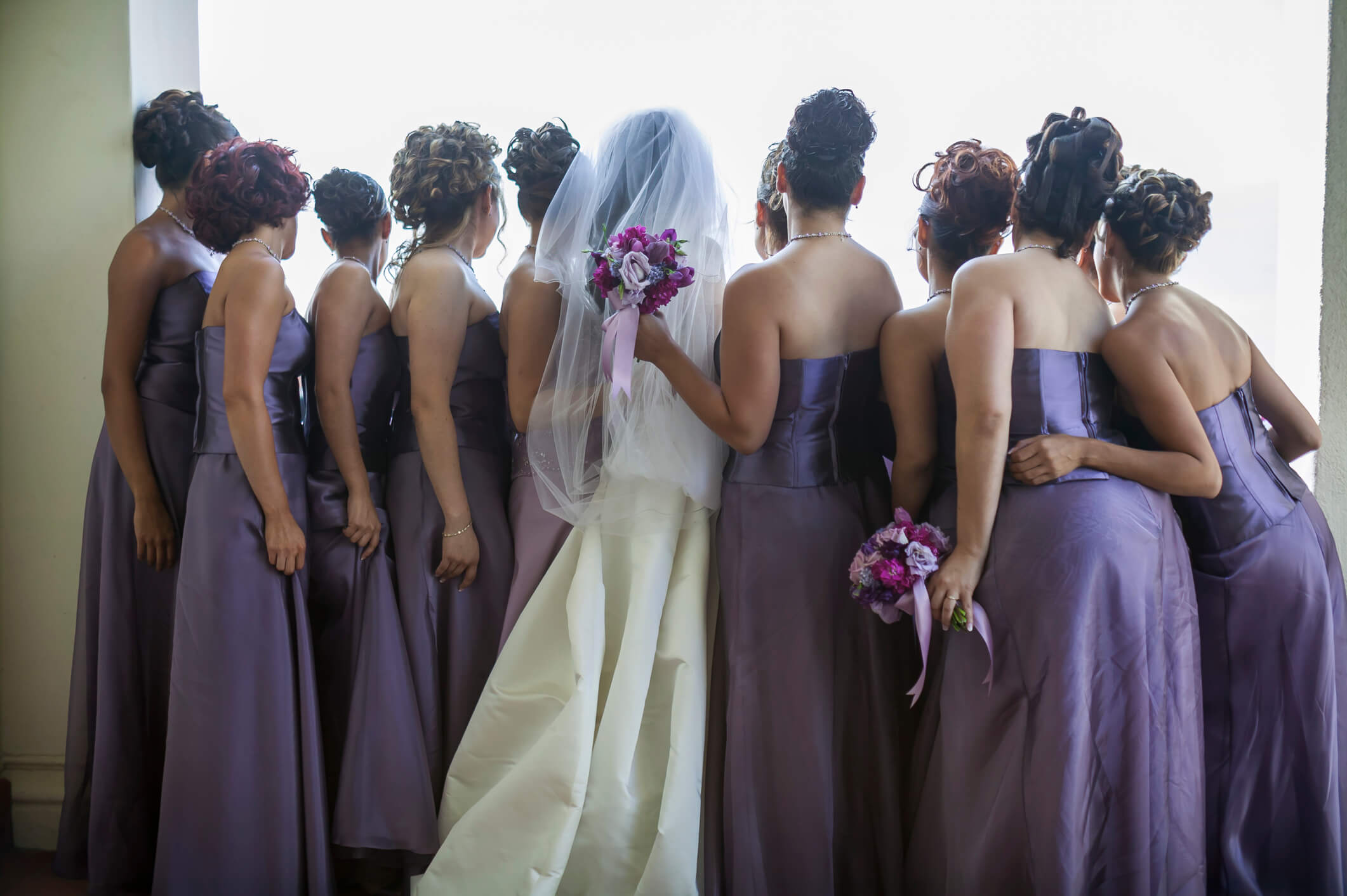Bridesmaids either side of a bride in purple dresses