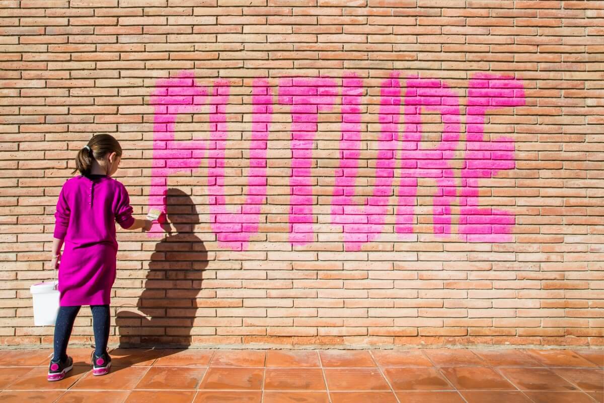 A girl painting the word 'FUTURE' onto a brick wall