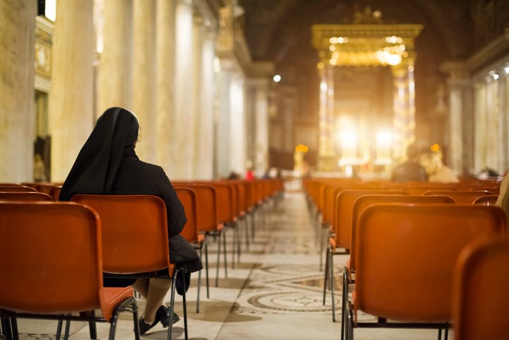 A nun sitting on the seats of a church