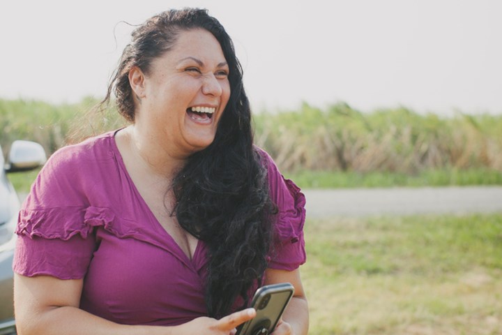A woman holding her phone and laughing