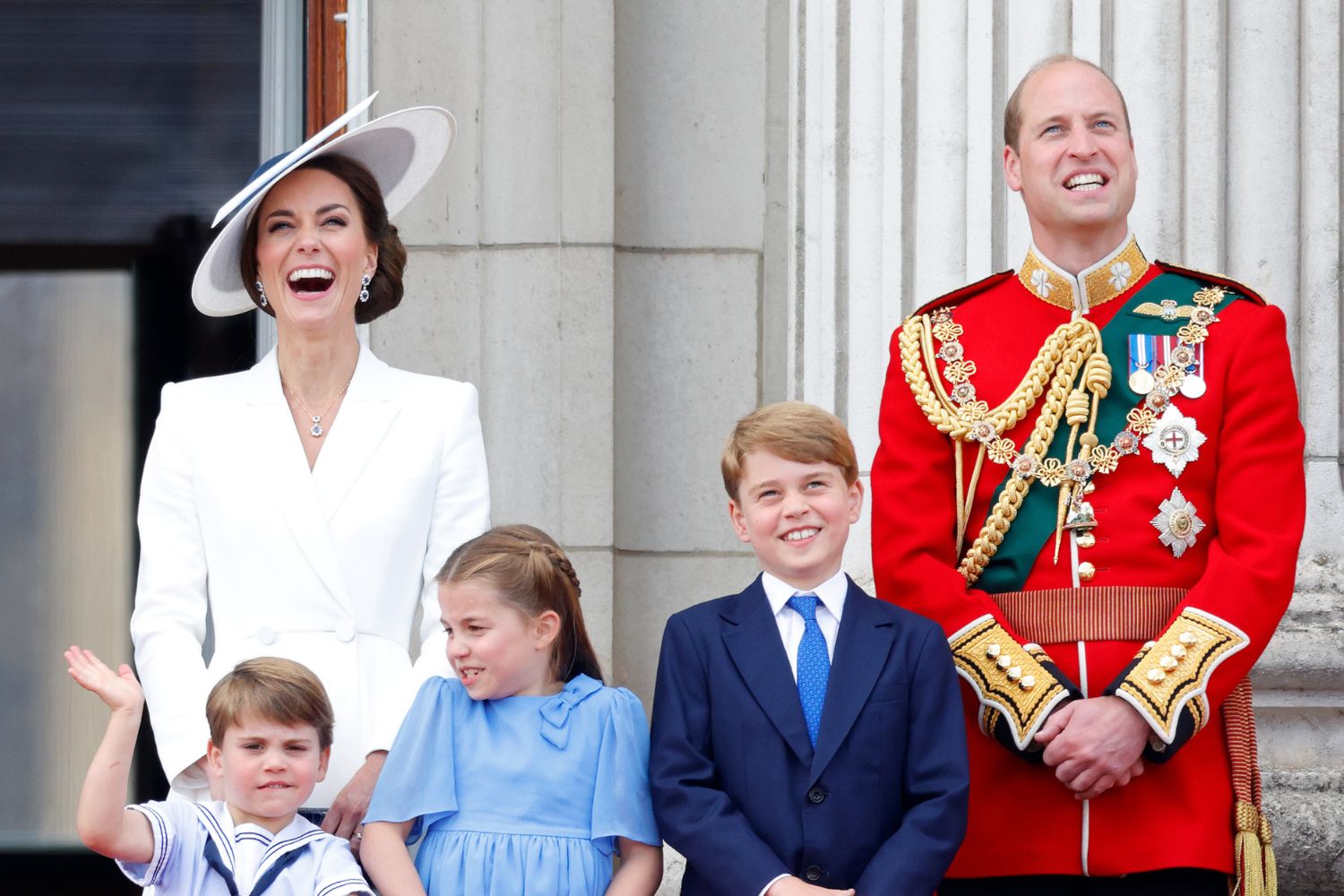 A smiling family stands together in formal attire, with one person in a red uniform.