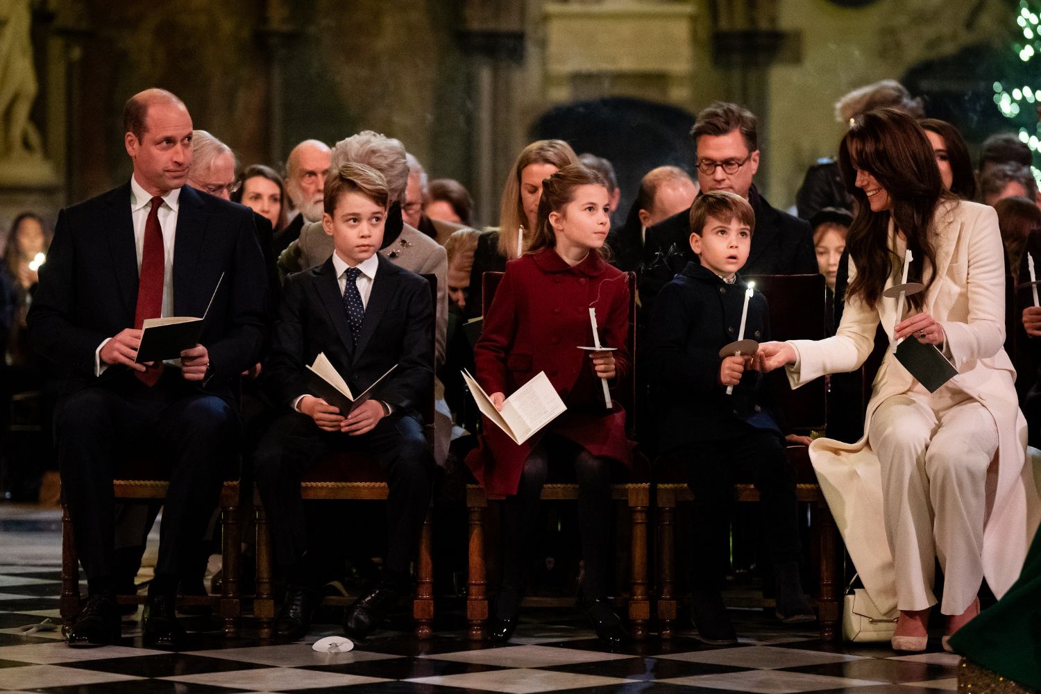 A family seated in a church, holding candles and programs, surrounded by others at a service or event.