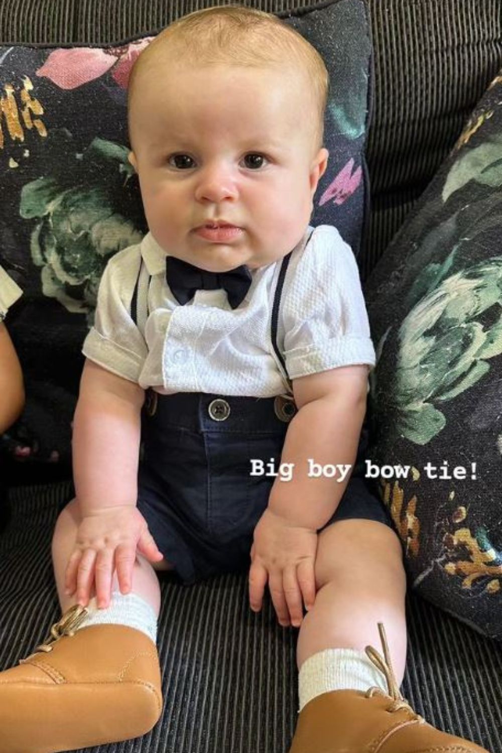 Baby wearing a bow tie and suspenders sitting on a sofa, labeled "Big boy bow tie!"