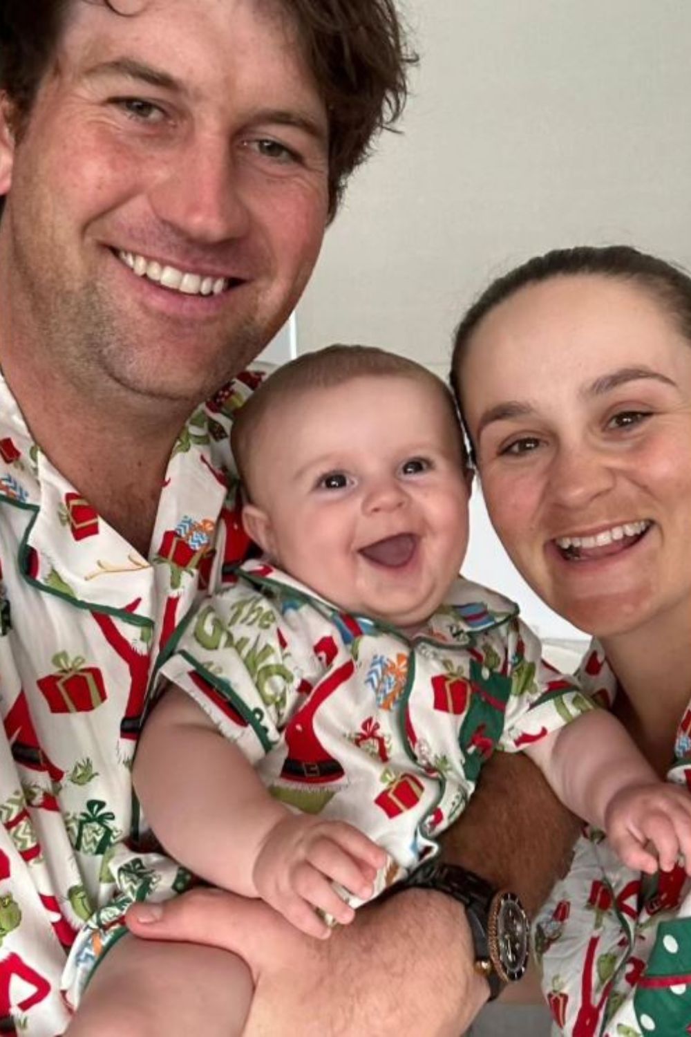 A happy family dressed in festive matching attire, with a smiling baby in the center.