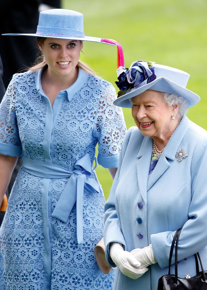 Princess Beatrice and Queen in matching blue outfits with hats, outdoors, smiling.