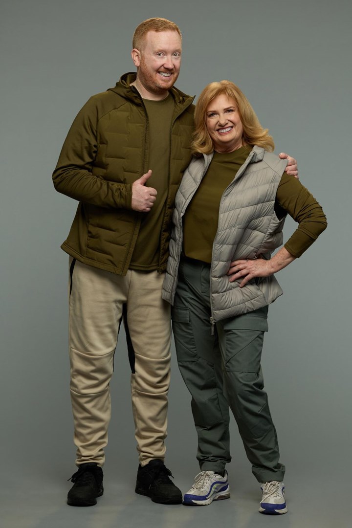 Man and woman in casual sportswear posing together, smiling with thumbs up in studio.