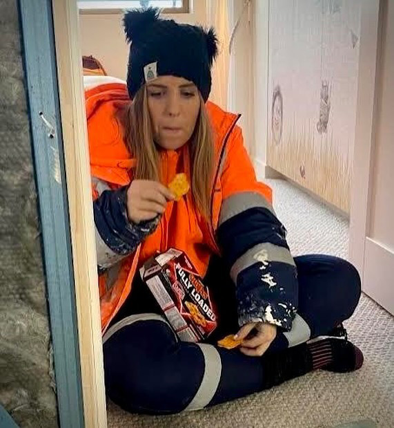 Eliza from The Block sitting on the ground eating snacks.