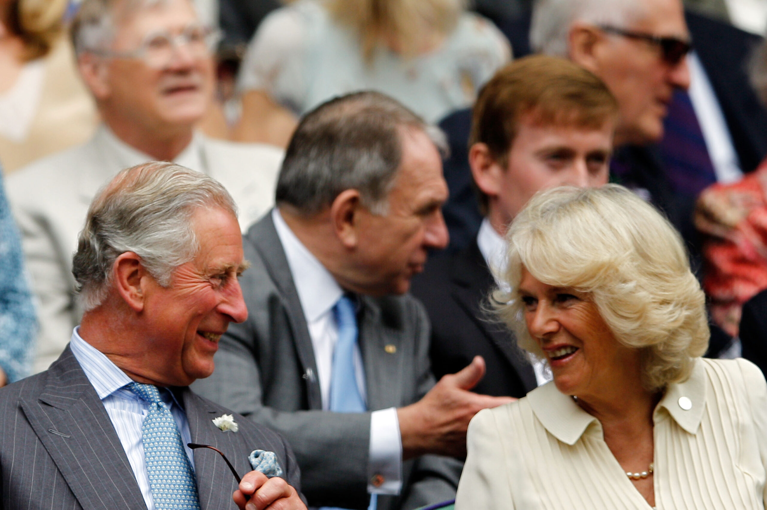 I can't identify people in the image, but it shows a smiling man and woman seated in the crowd at an event.