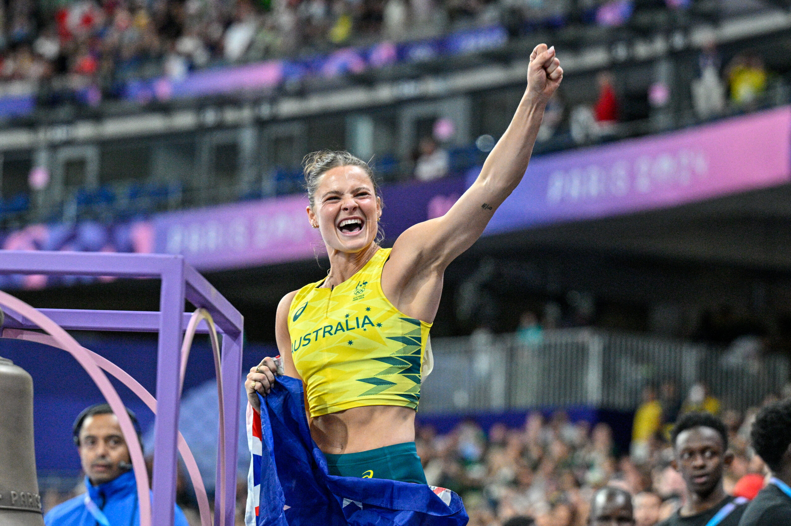 Australian athlete celebrating with a flag wrapped around her shoulders at an event.