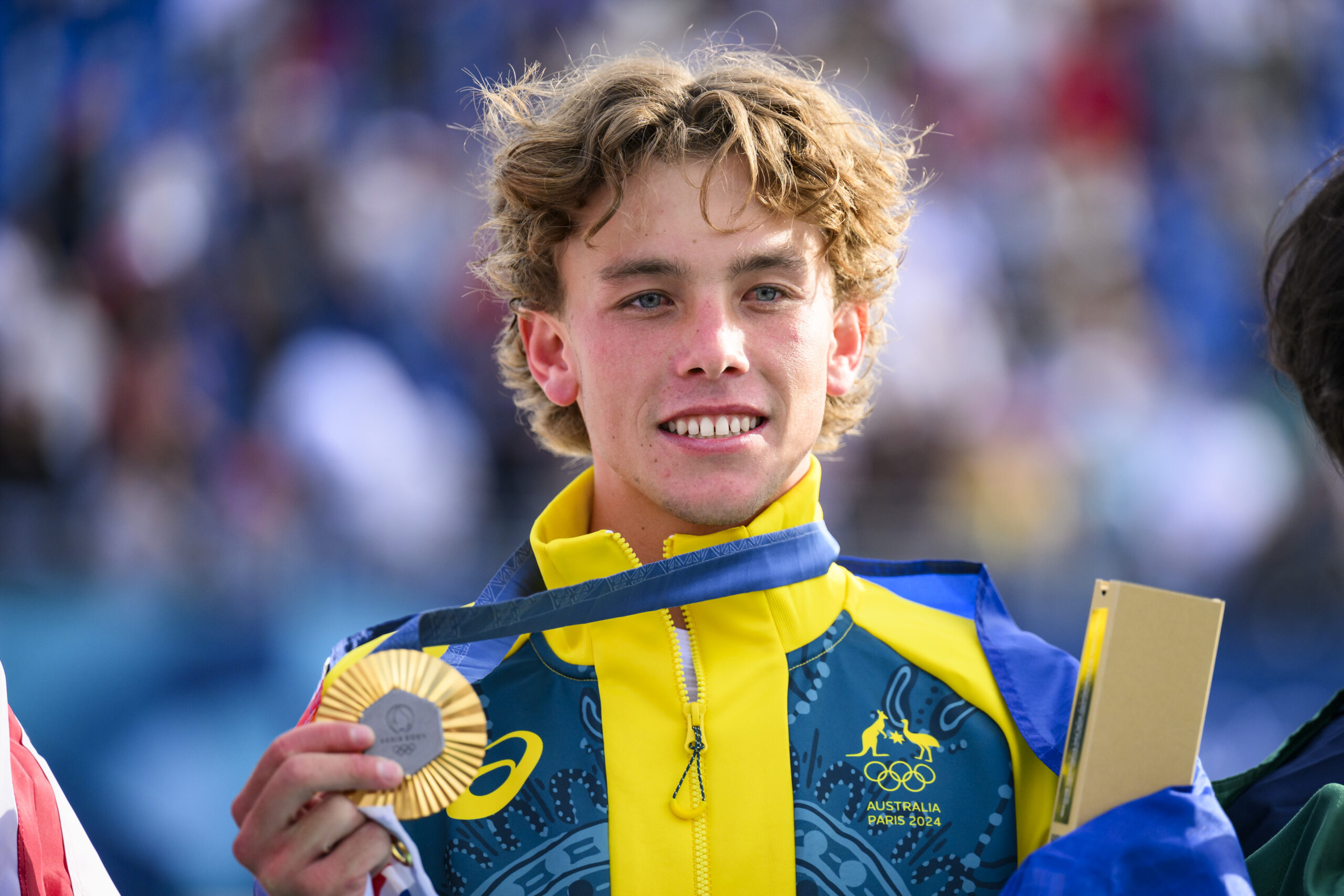 Young athlete in an Australian outfit holding a silver medal at an event.