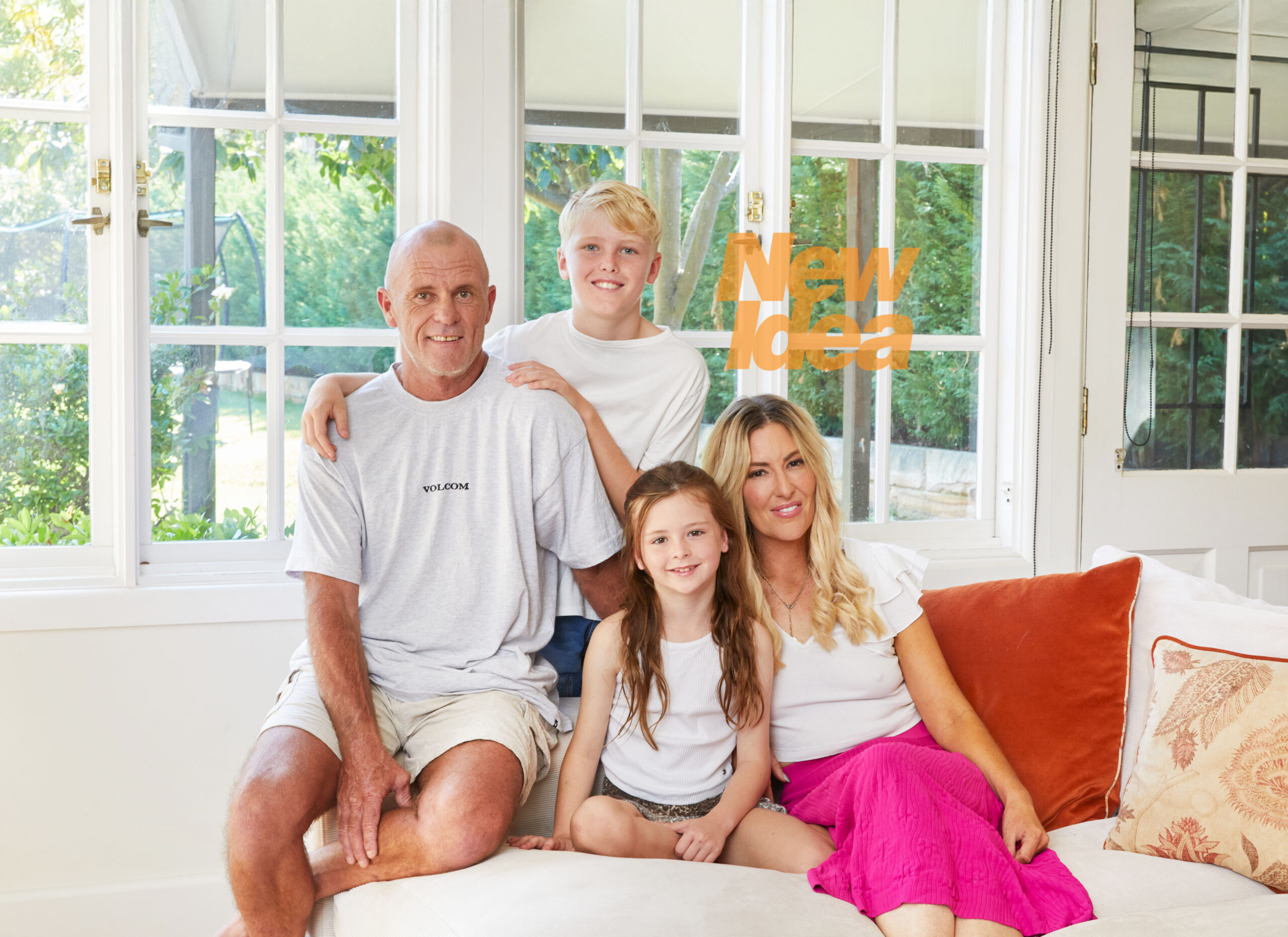 Jess Eva, Norm Hogan and their children Freddie and Matilda sitting on a white couch in front of a window.