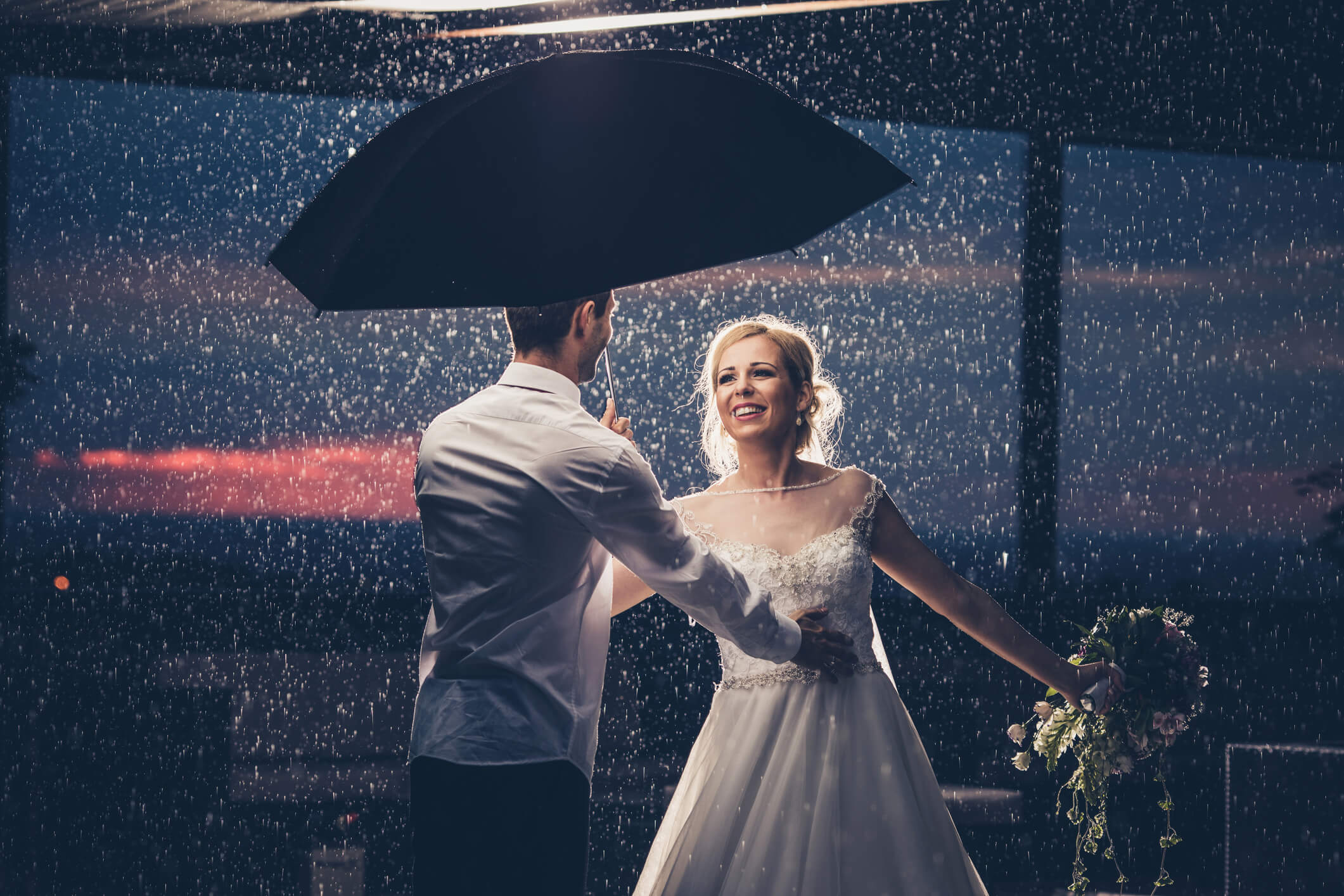 A newlywed couple under an umbrella